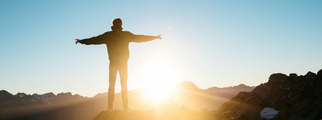 A man on a hill with his arms outstretched
